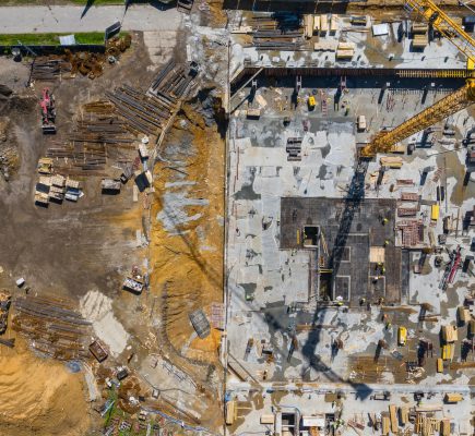 Contstruction Site from above. Aerial view of new apartment under construction. People working. Top view industrial place.