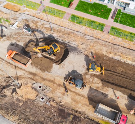 Construction of a city street, laying of communications, installation of sewer hatches, gutters, curbs. Preparation for paving, aerial view