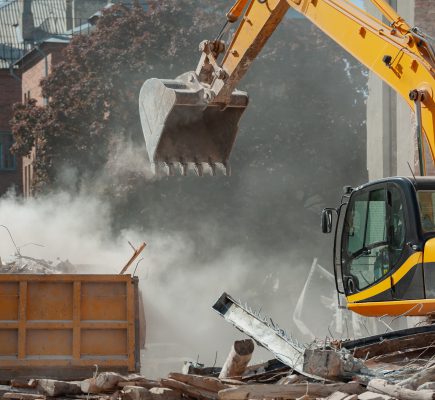 Demolition of building. Excavator breaks old house. Freeing up space for construction of new building.