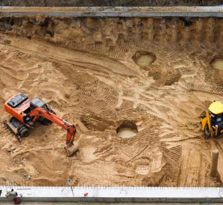 Construction of concrete foundation of new building. Construction machinery, excavators, top view.